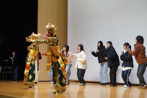 動きを教わり見よう見まねで踊る学生